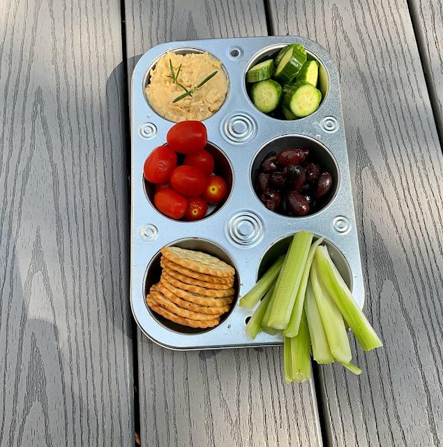 muffin tin filled with vegetables and hummus