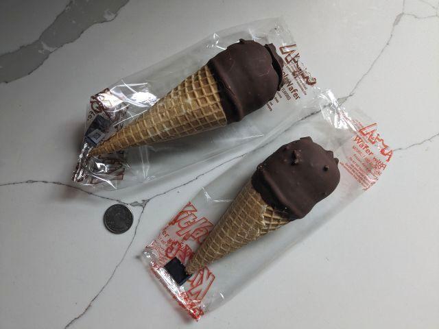Two Kit Kat Cones unwrapped and next to a quarter.