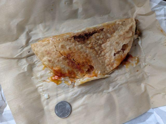 A Taco Bell Caliente Cantina Chicken Crispy Taco next to a quarter.