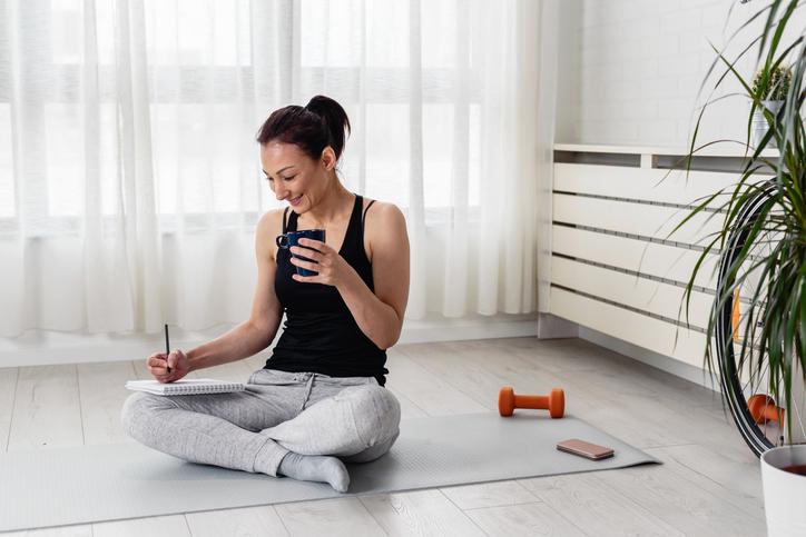 Woman Records Goals and Accomplishments in Notebook after Workout | Deload Week