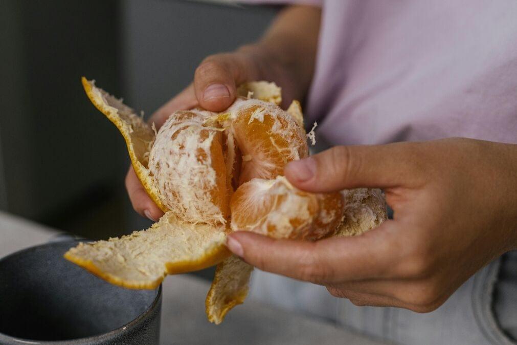 Female hands peeling a satsuma.