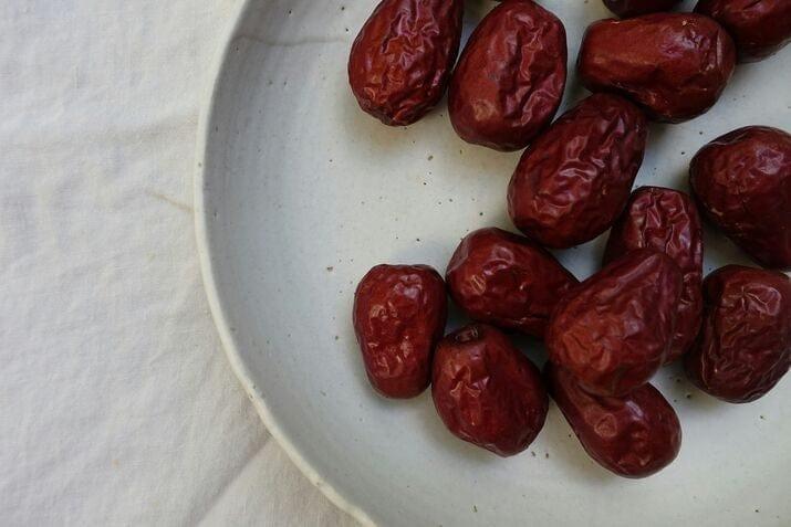 Dark brown medjool dates in a white ceramic bowl