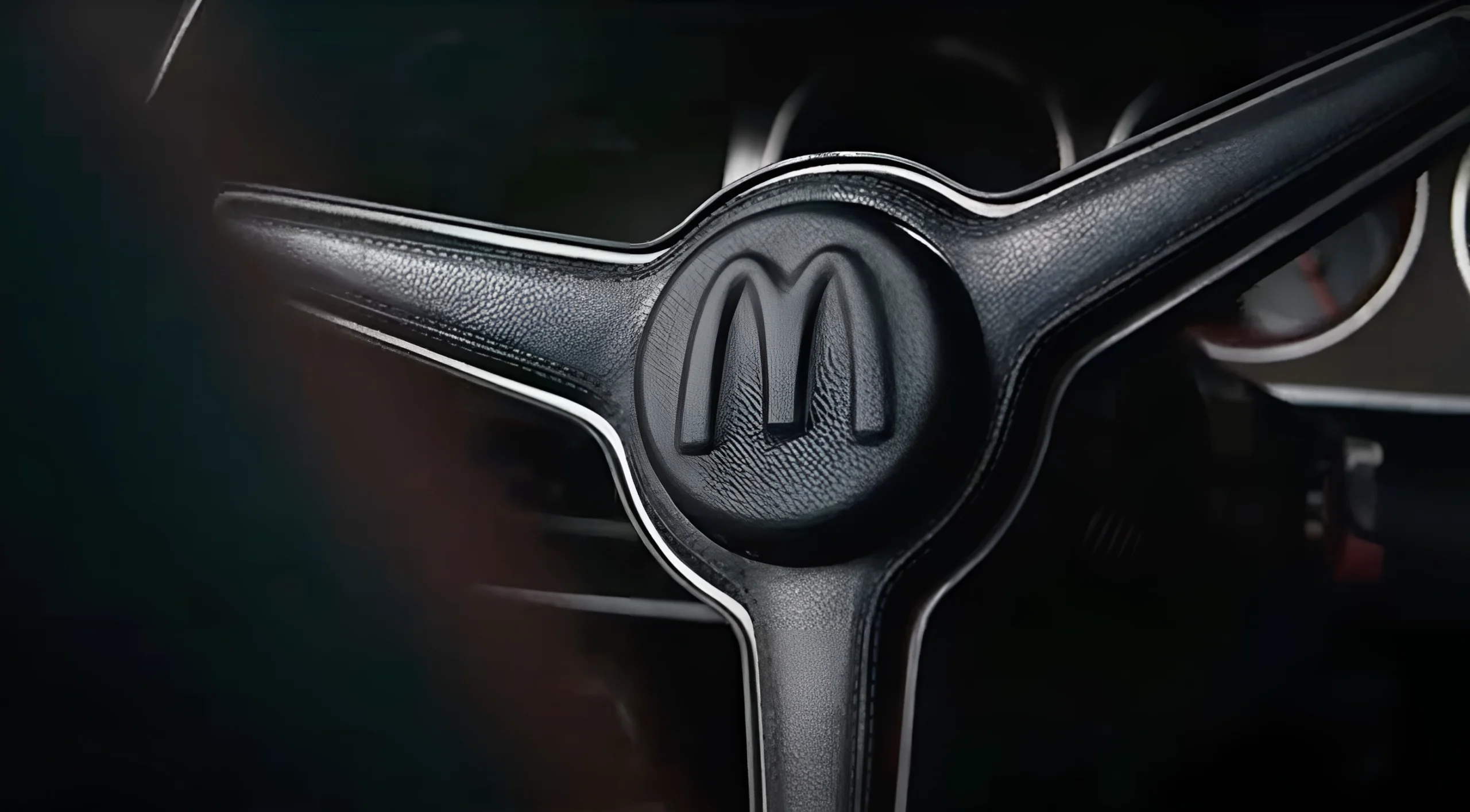 A close up of the steering wheel of a classic car.