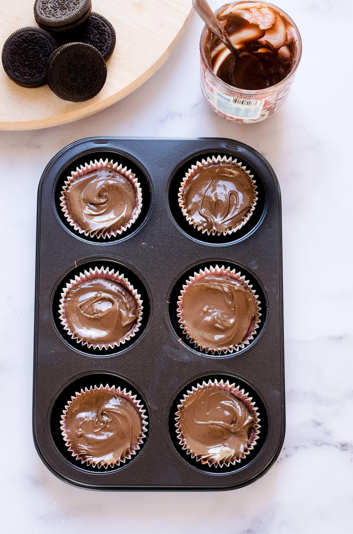 Mini cheesecakes topped with Nutella in a muffin pan