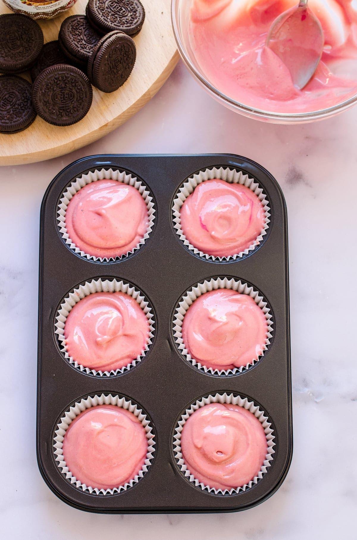 A muffin pan with mini red velvet cheesecakes ready to be baked