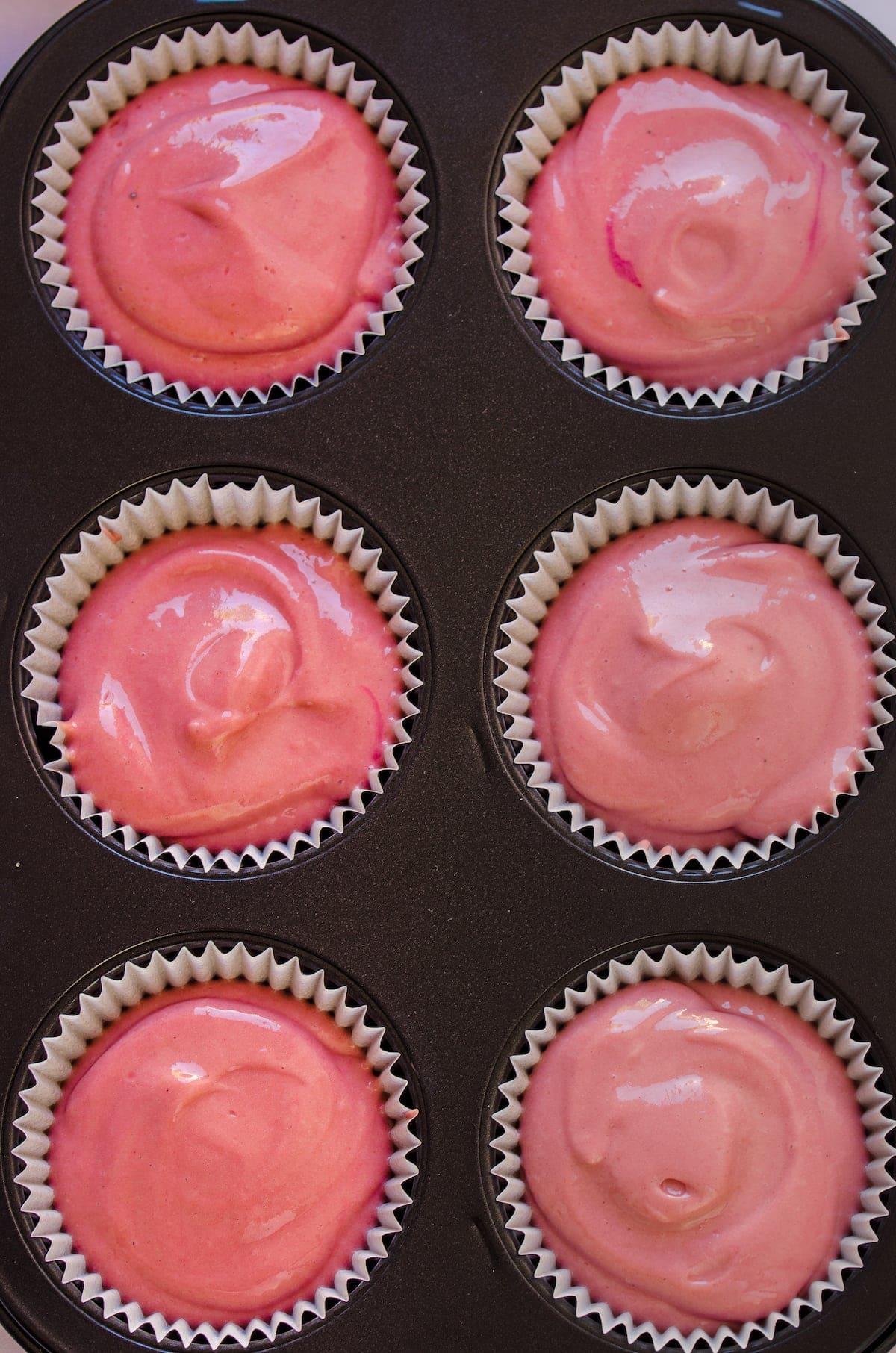 Overhead view of mini red velvet cheesecakes in a muffin tray