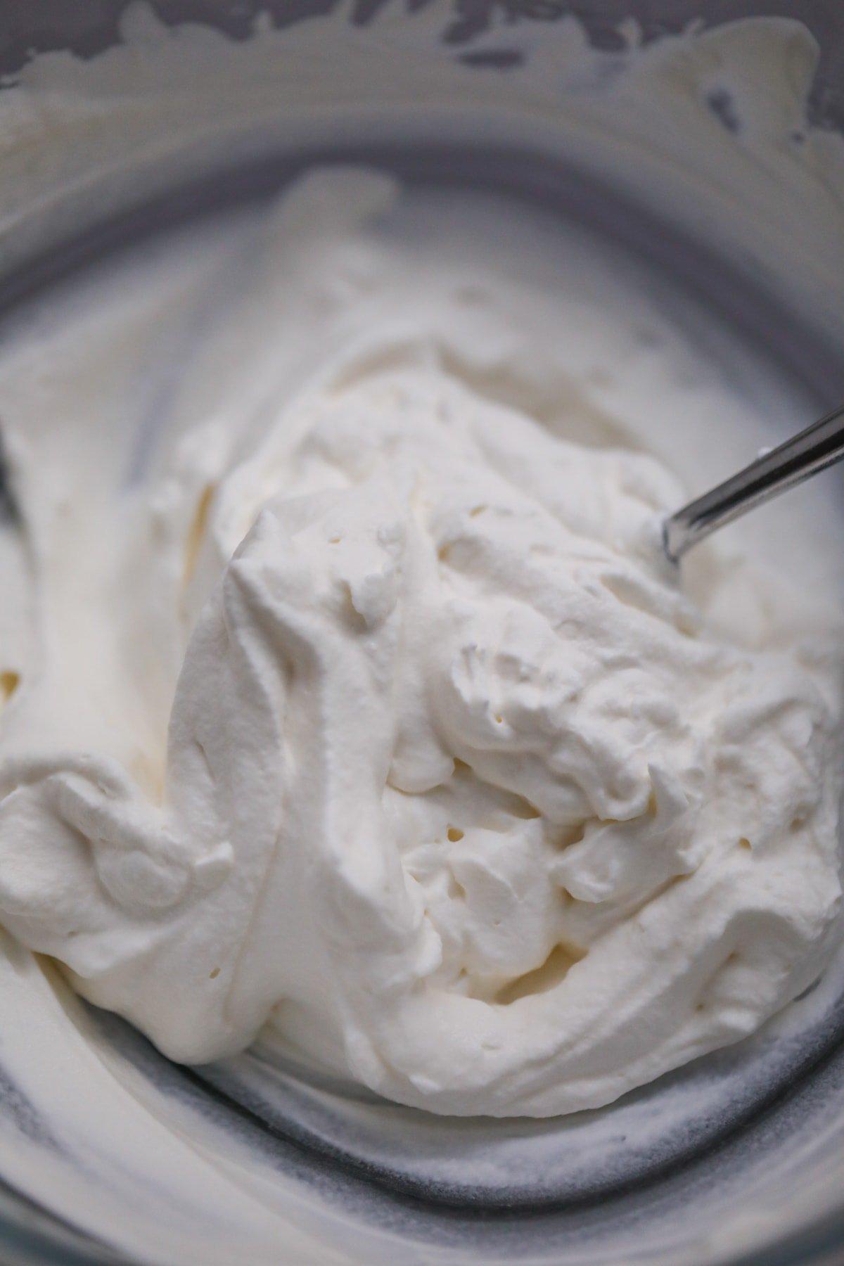 whipped cream in a bowl with a spoon in it