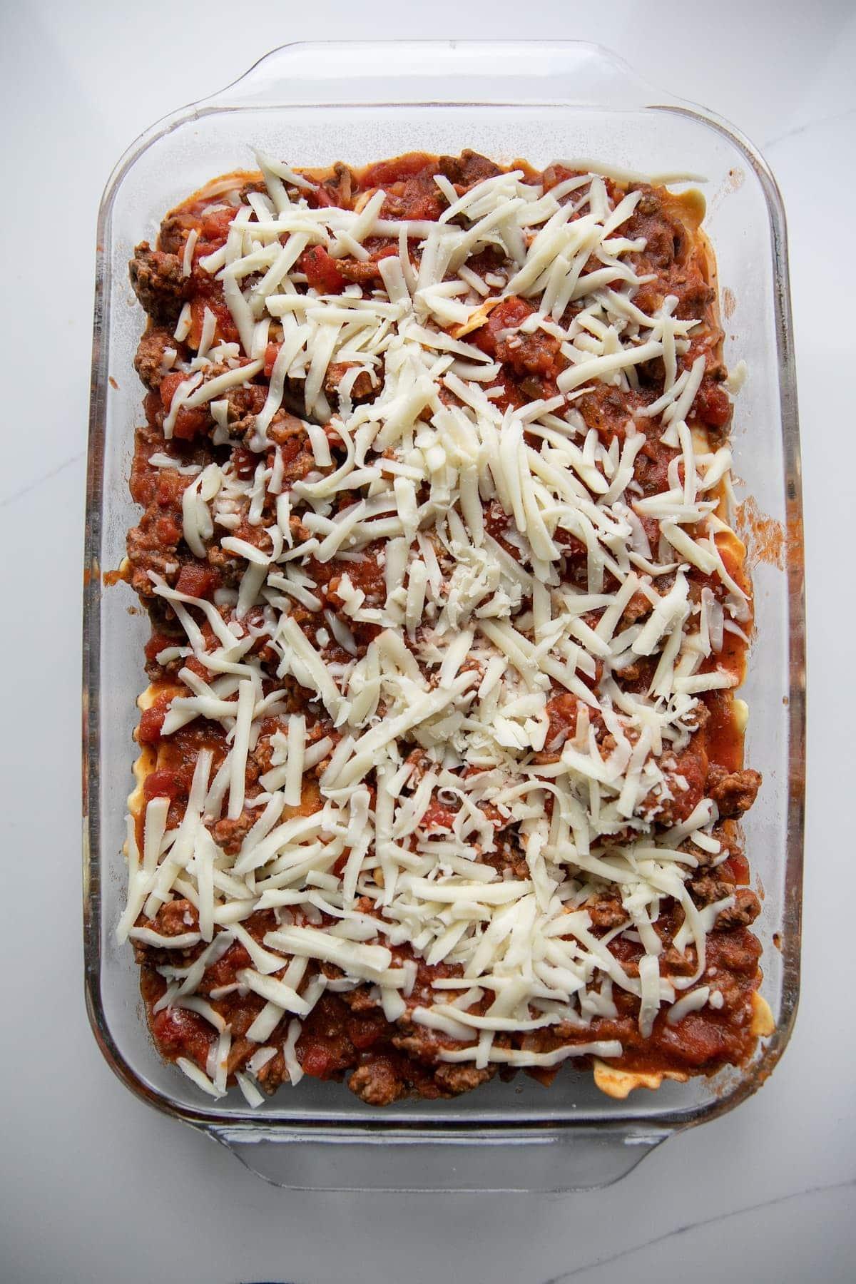 layering ravioli with sauce and cheese