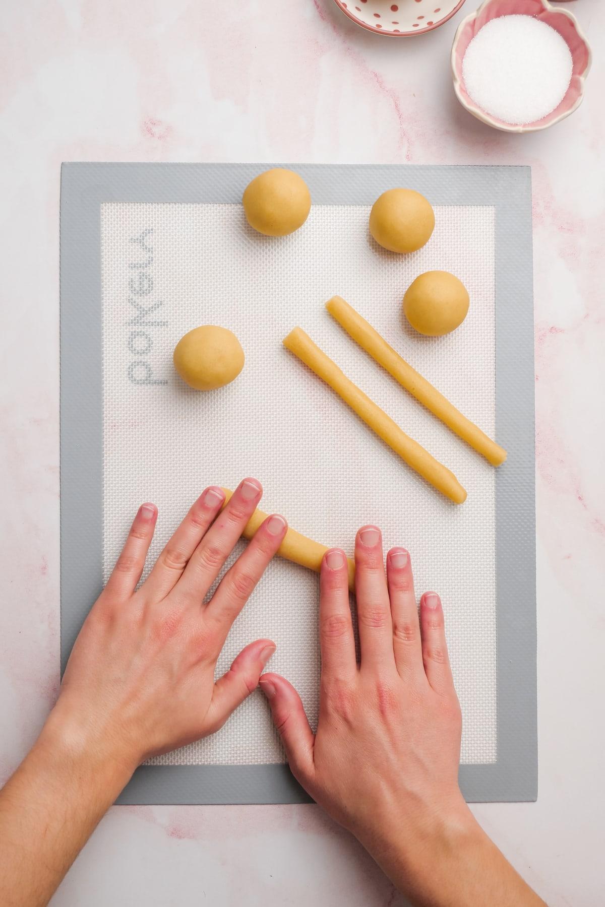 valentines day cookies 12 woman's hands rolling dough into skinny "snakes"