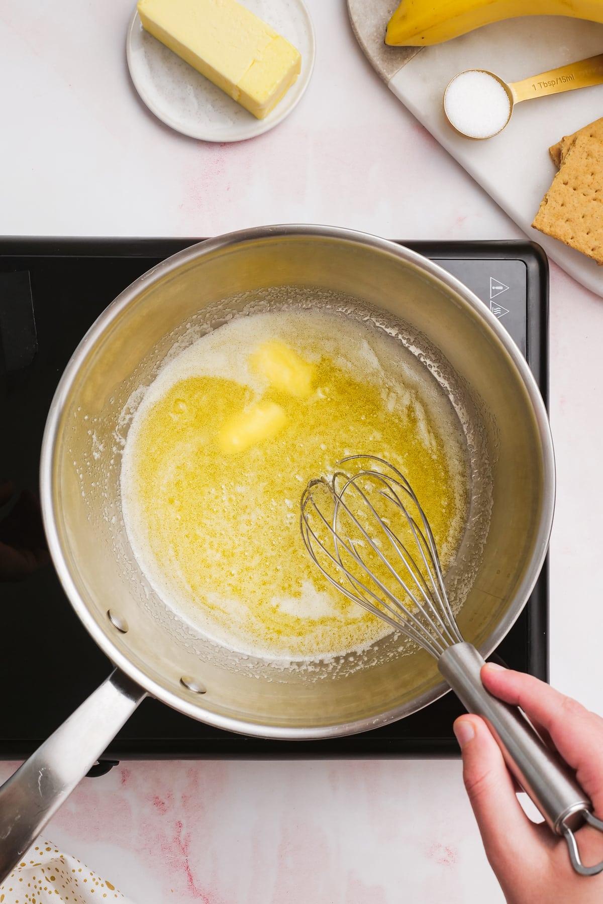 woman's hand using a whisk while melting butter in a pan