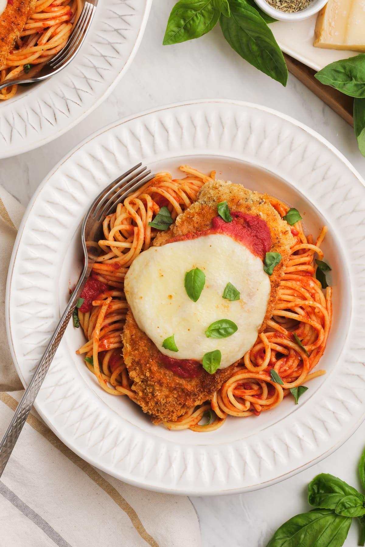chicken parmesan in a bowl over pasta and marinara sauce