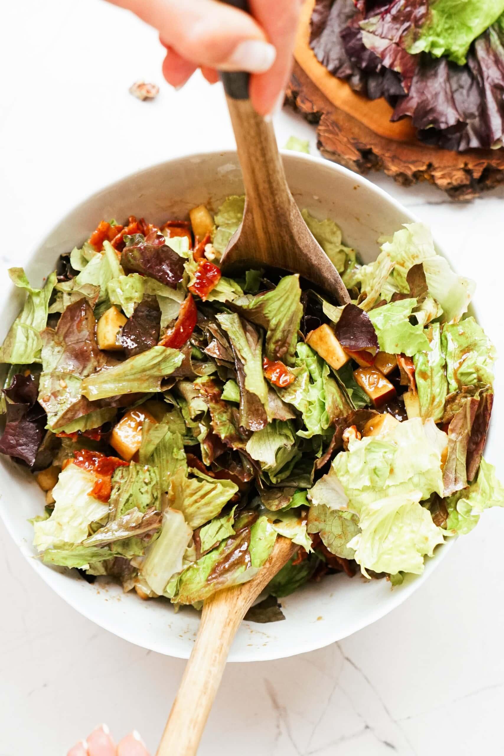 apple pecan salad in a bowl with large wooden spoon
