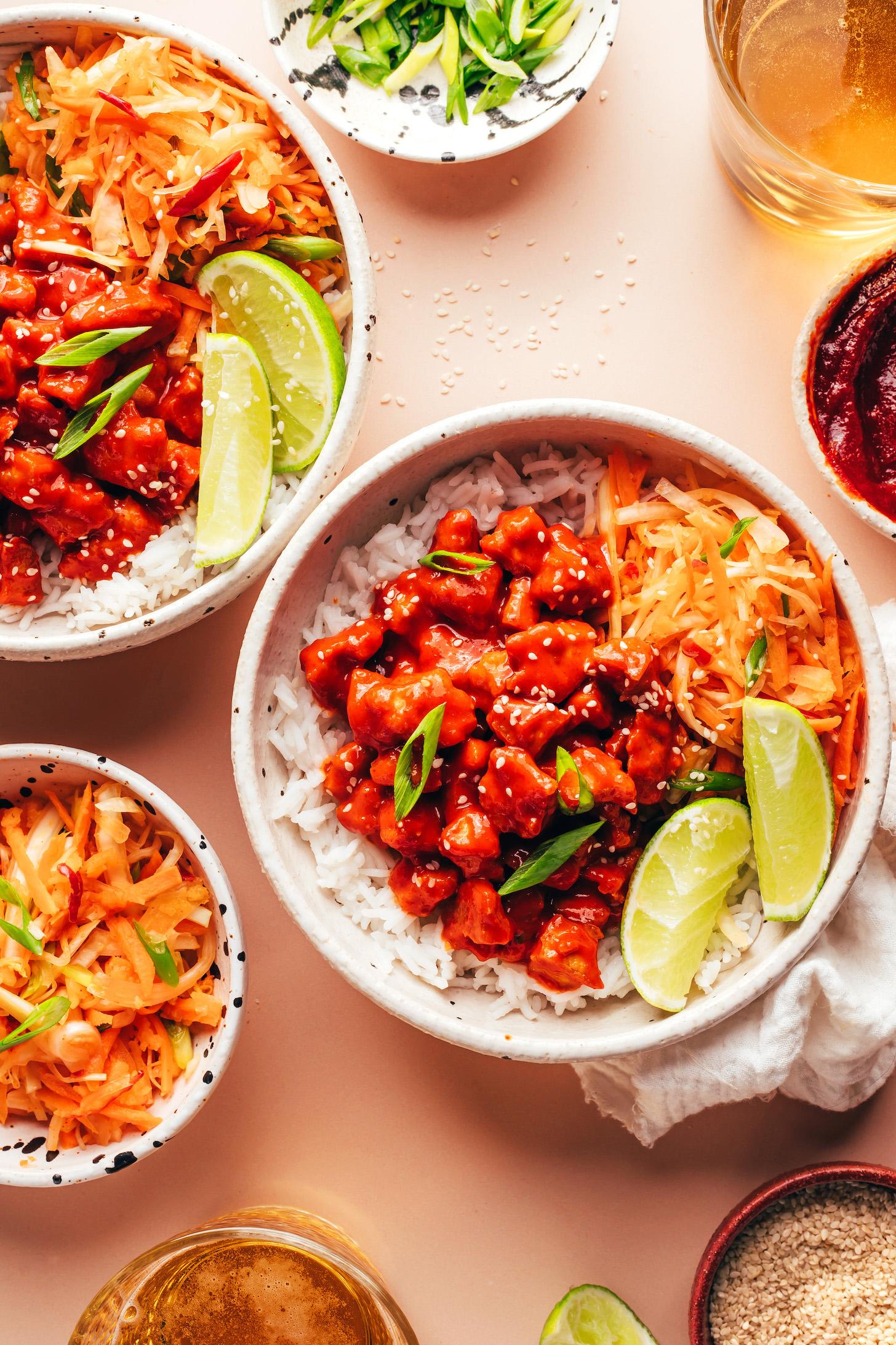Overhead shot of bowls with gochujang tofu, white rice, and Korean-inspired cabbage apple slaw