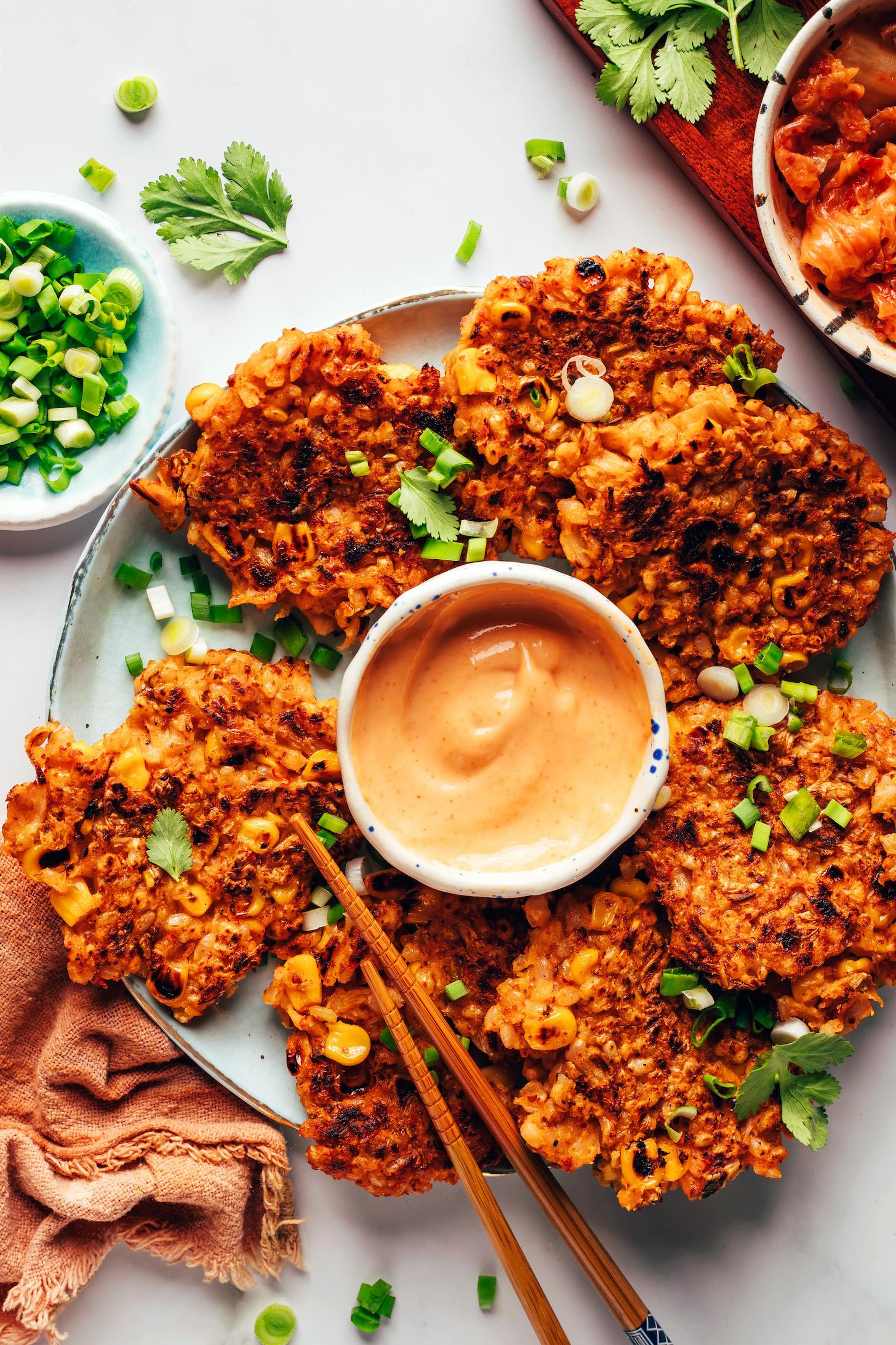 Platter of kimchi rice fritters surrounding a bowl of sriracha sour cream sauce