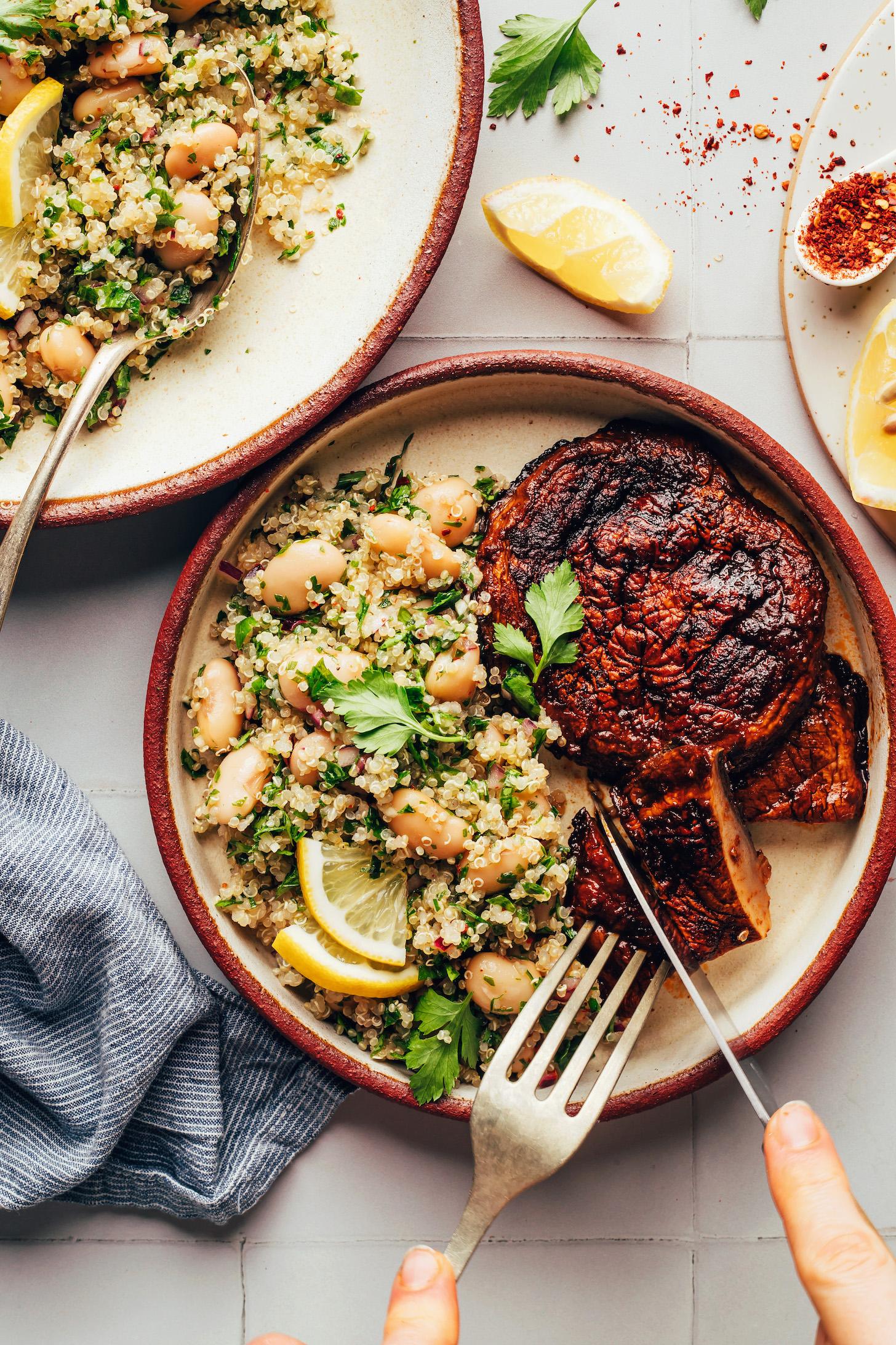 Slicing into a portobello steak on a plate with a side salad