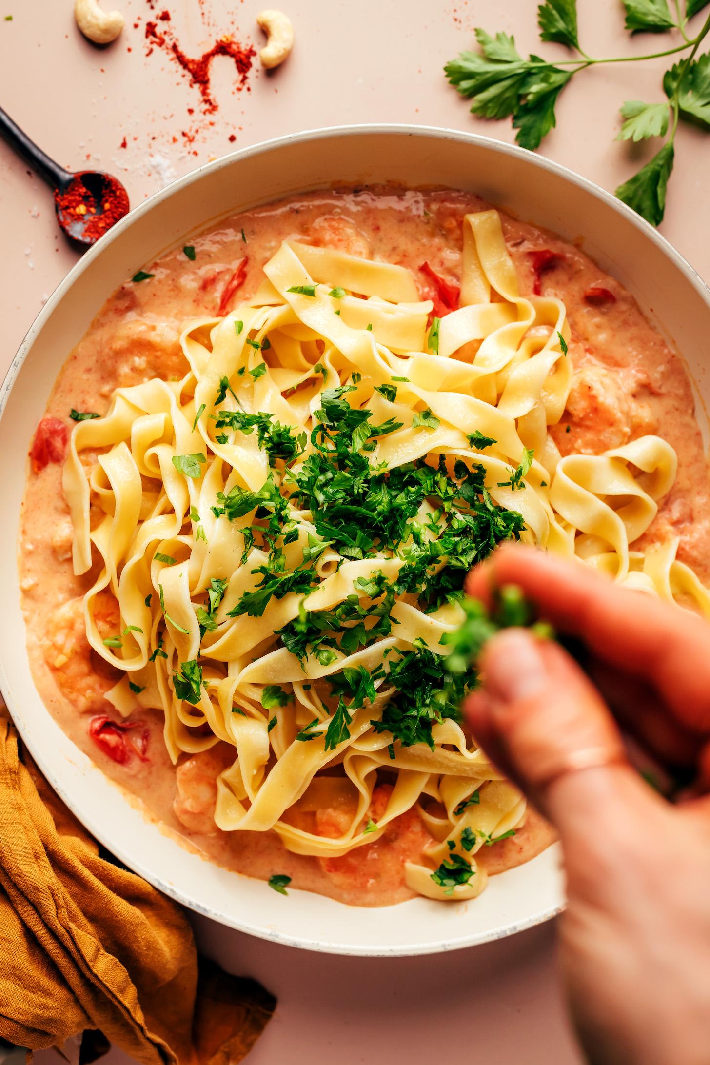 Sprinkling fresh parsley over pasta