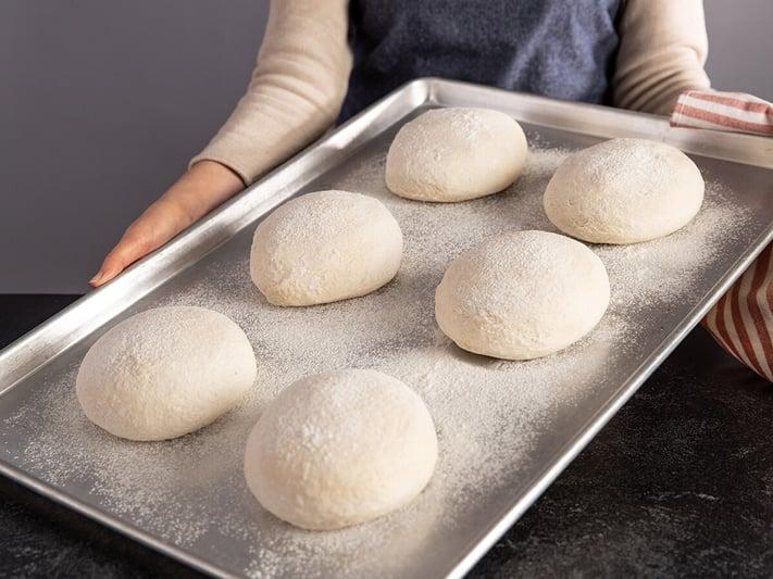 prepped pizza dough on a cooking sheet